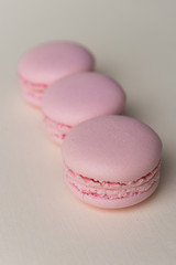 Three sweet purple macaroons on white table background.