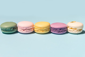 Five sweet colorful macaroons on blue table background.