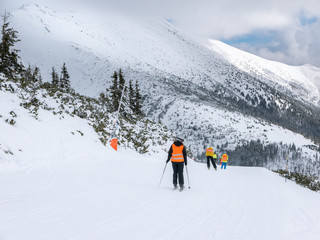 Fototapeta na wymiar Rear view of skiers in vests from ski school.