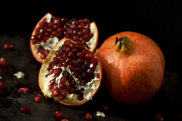 Whole and Broken Open Pomegranate on Black Background