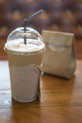 Paper cup of iced coffee on wooden table