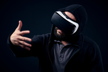 Young hipster bearded man wearing virtual reality goggles. Black background studio VR concept