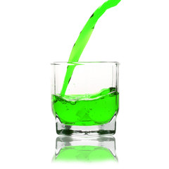 green cocktail splashing on a glass on white background