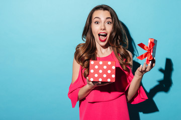 Excited cute girl in dress holding opened present box
