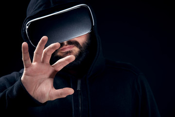 Young hipster bearded man wearing virtual reality goggles. Black background studio VR concept