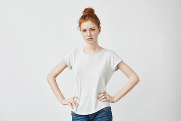 Pretty girl with ginger hair looking at camera 
with arms akimbo.