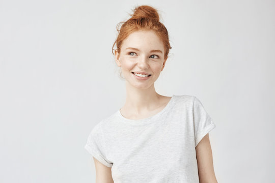 Portrait of playful beautiful ginger girl with freckles smiling.
