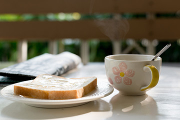 Hot coffee with milk and newspaper Put on a white wooden table with morning sunshine.