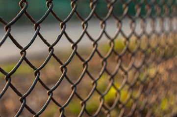 Sunset view over the city through the wire mesh fence, close up shot