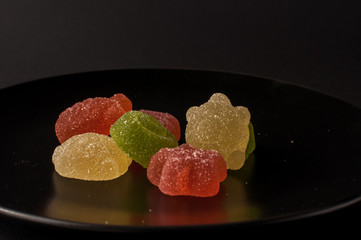 Close-Up Of Colorful Candy. mixed fruit flavoured jellies on a black plate