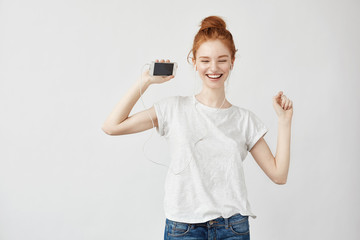 Obraz premium Beautiful redhead girl listening music in headphones laughing.