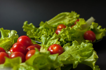 Healthy vegetarian Salad cherry tomatoes and lettuce on the black plate