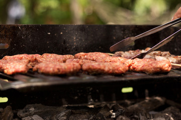 Grilled shish kebab and meat balls on barbecue at picnic also on background there are picnic table and hammock in frame