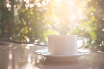 White coffee cup on the table with the sun as a backdrop.