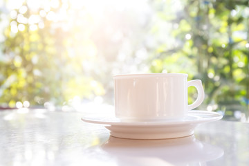 Obraz na płótnie Canvas White coffee cup on the table with the sun as a backdrop.