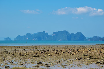 reef rocks or submerged rocks on the beach and the islands on blue sky day in background