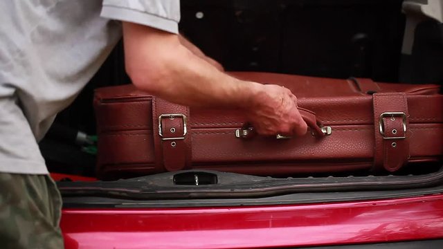 video man loads the suitcases in the car