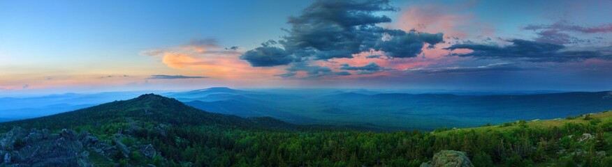 Naklejka na ściany i meble Sunset over the mountainous terrain. The nature of the Southern Urals. Sunset sky over the forest and the mountains.