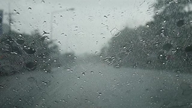 Raindrop on glass front of my car and wipers working while driving on road at Nakhon Nayok, Thailand