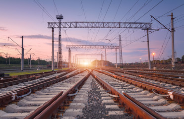 Modern railway station at night in Europe. Industrial landscape with railroad junction, purple sky...