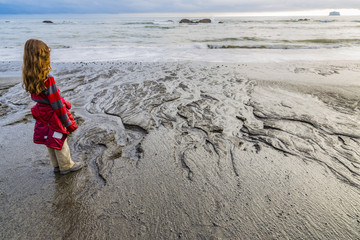 Boy looking out to the sea from a beach in the pacific northwest