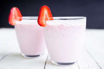 Blueberry smoothie with fresh strawberry on white wooden table. Fresh milkshake