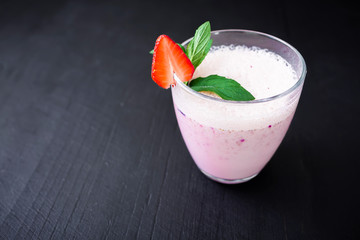 Blueberry smoothie with fresh strawberry on white wooden table. Fresh milkshake with berry