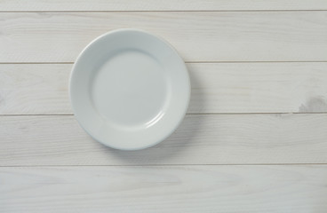 Obraz na płótnie Canvas Plato blanco vacío en mesa de madera blanca y pared azul