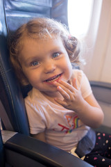Little laughing girl is traveling by plane.