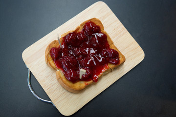 Strawberry jam toast on  wooden plate, Black background