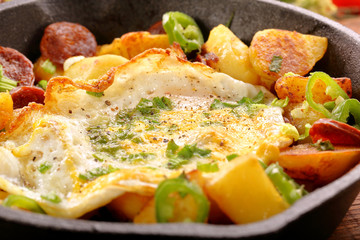 fried egg and baked potatoes with sausage chorizo on frying pan