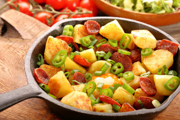 Baked potatoes with sausage chorizo and fried egg on frying pan