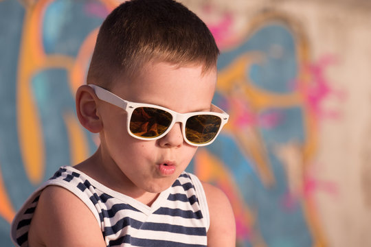 Funny little boy wearing trendy sunglasses and sailor stripes shirt