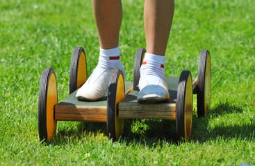 Junge in Turnschläppchen balanciert auf einem Pedalo auf dem Sportplatz