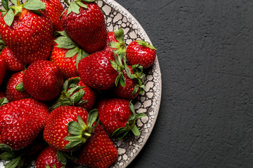 fresh ripe useful fruit strawberry in a clay bowl closeup on a black background