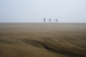 Fototapeta na wymiar Surfers walking in the mist