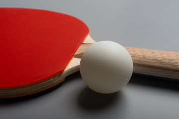 pingpong rackets and ball on a grey background