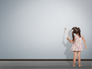 child writing with paint brush on empty wall, back view