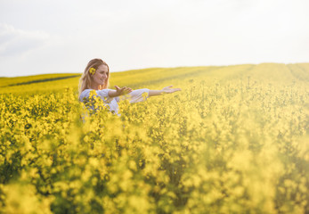 Smiling woman in yellow rapeseed field at sunny day