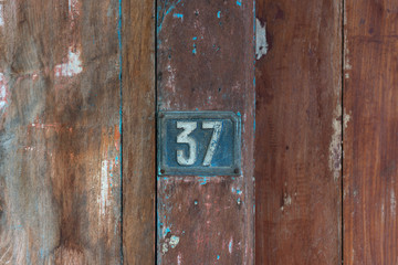 Old metal number 37 plaque on a old wooden door.