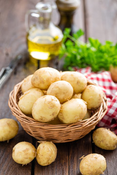Raw potato in basket on wooden table closeup