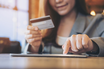 An Asian business woman holding credit card while using tablet in coffee shop