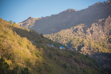 Nepal Snowy mountainPanoramic view from the mountain top showing green valleys, hills, misty clouds, and a scenic village in the landscape