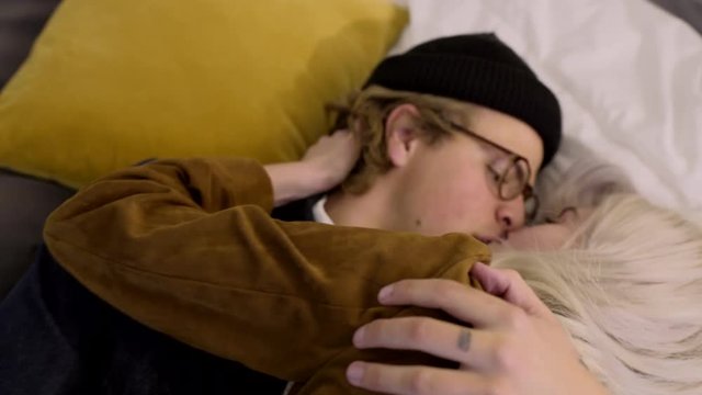 Closeup Of Smiling Man, His Playful Girlfriend Jumps On Him, And They Fall Into Bed And Kiss