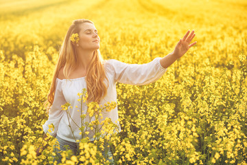 Naklejka na ściany i meble Smiling woman in yellow rapeseed field at sunny day
