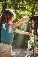 boy playing with water from a pump at a campsite