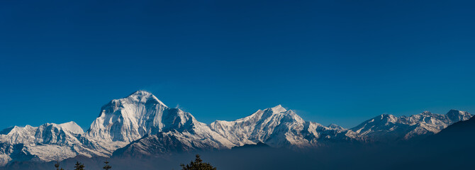A panoramic view of snow-covered mountains in winter with clear blue skies in the Alps