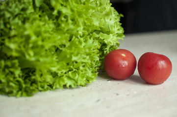 Bunch of raw organic green frisee salad and two tomatoes