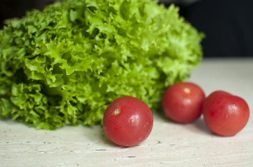 Bunch of raw organic green frisee salad and two tomatoes