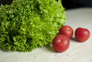 Bunch of raw organic green frisee salad and two tomatoes